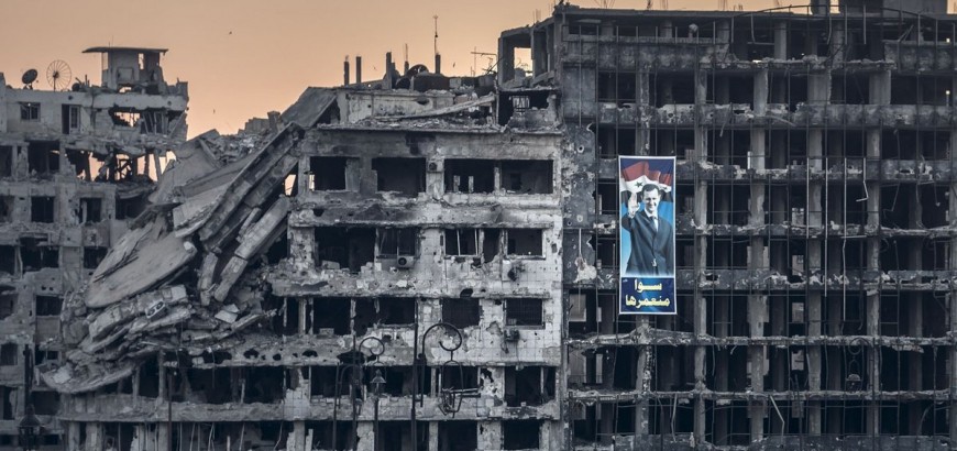 صورة لبشار الأسد وسط ركام المباني التي دمرتها طائرات جيشه في مدينة حمص (وسط سوريا)